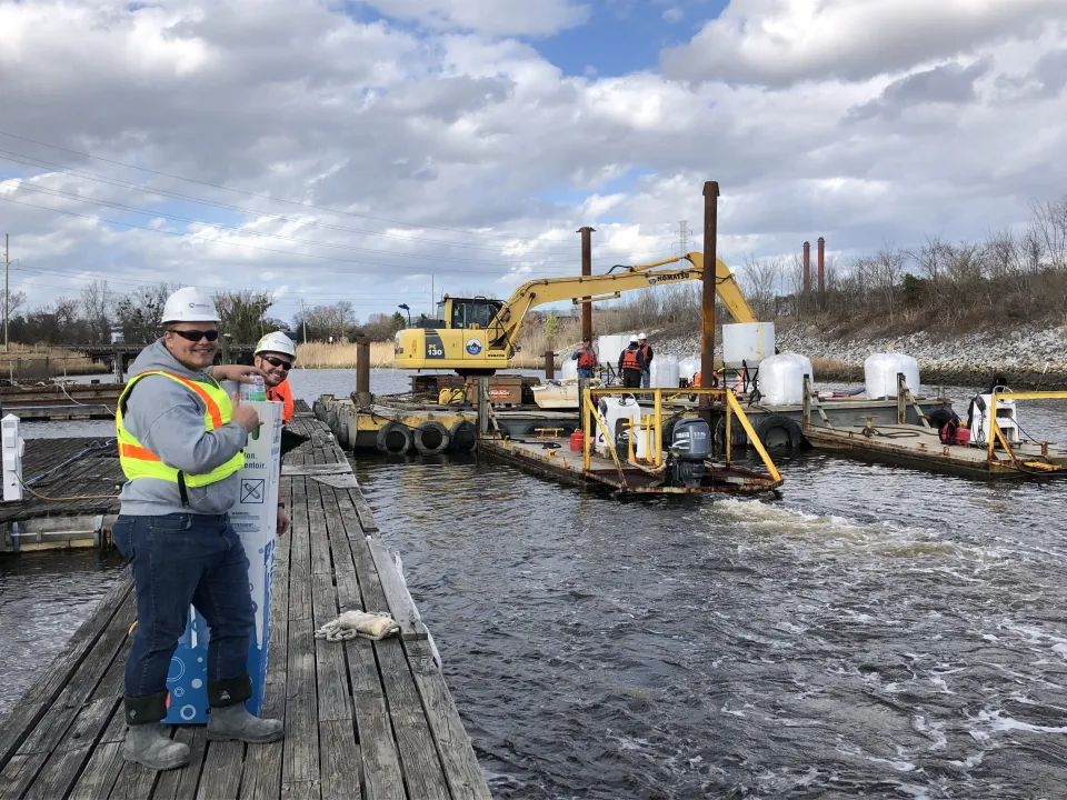 Workers deploy a carbon barge as part of the process of replacing contaminated sediment at the bottom of Paradise Creek in Portsmouth.