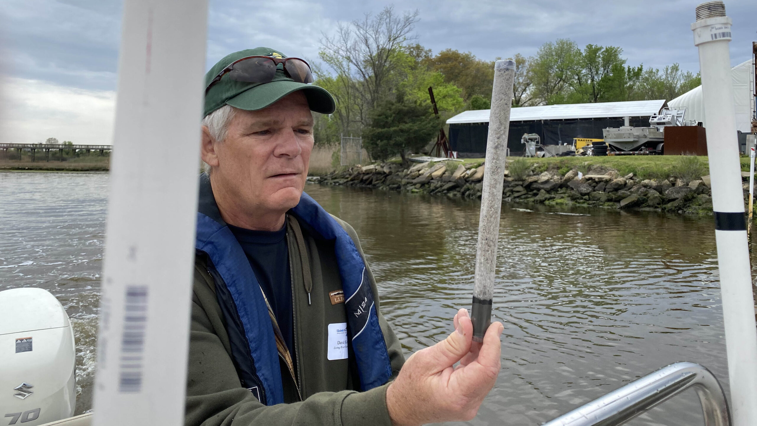 Dave Koubsky, restoration manager with the Coastal Virginia Conservancy, holds a tube in 2022 displaying clean sand and activated carbon to line Paradise Creek. (Photo by Katherine Hafner)